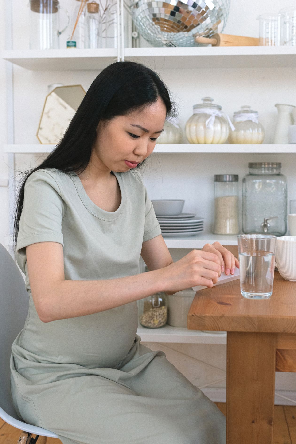Gestante preparando vitaminas pré-natais na cozinha, contexto de melhor polivitamínico para gestante