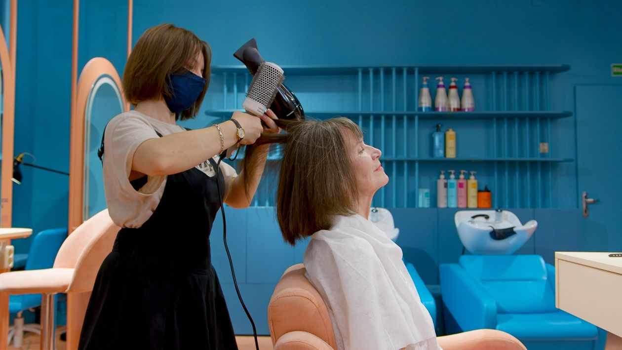 Secador de cabelo profissional em uso por cabeleireiro, contexto de salão de beleza