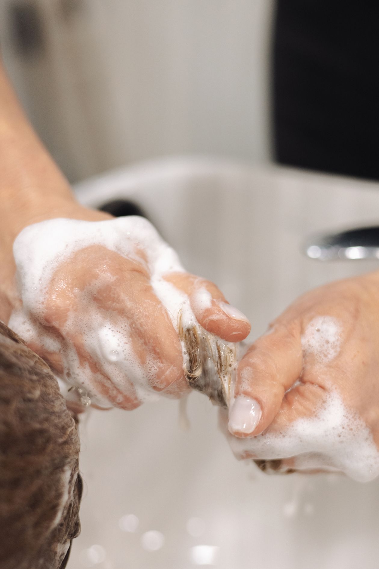 Mulher lavando o cabelo com espuma de shampoo, contexto de melhor shampoo Aussie para cabelos secos