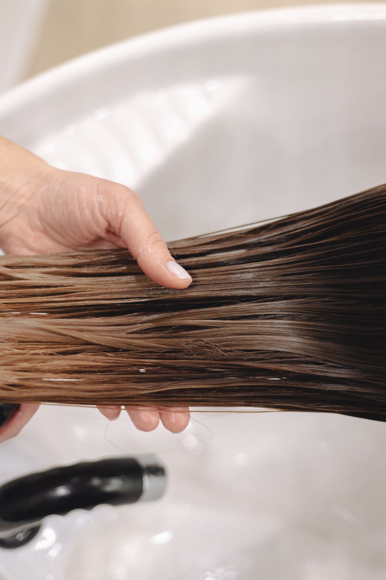 Mulher segurando as pontas do cabelo molhado, contexto de melhor shampoo da Elseve para cabelo danificado