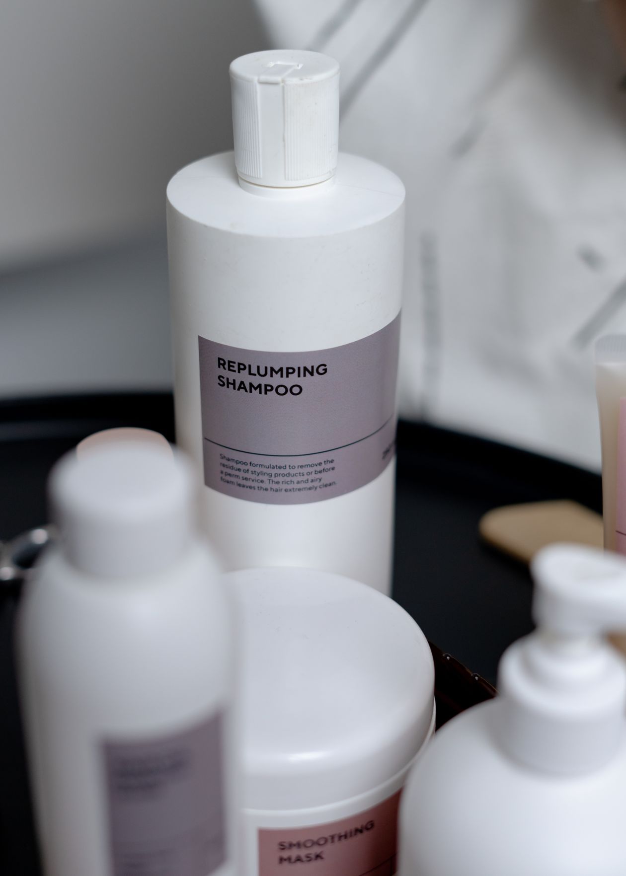 Frascos de shampoo profissional sobre bandeja de salão, comparação entre as marcas L'Oréal Professionnel e Wella Professionals