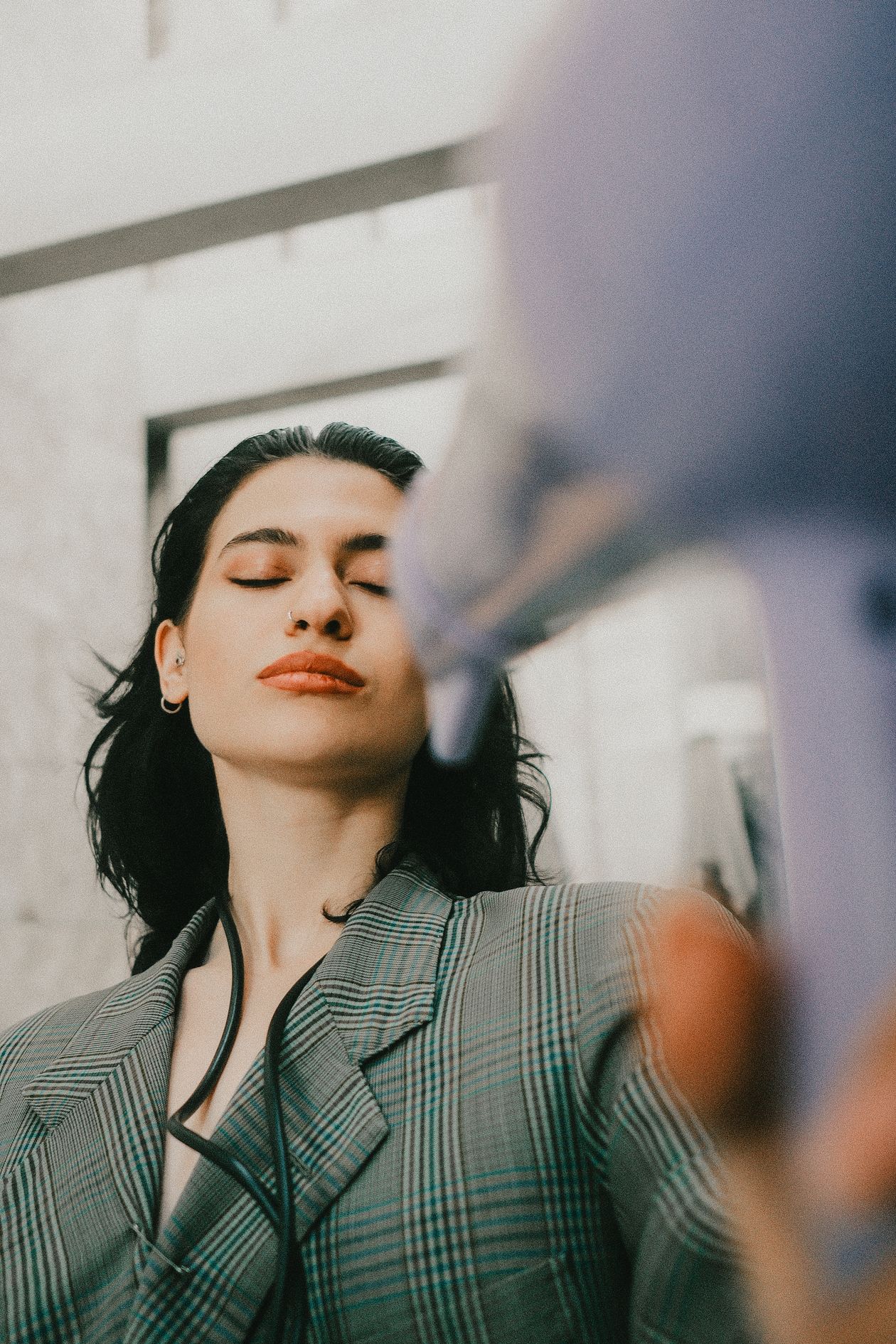 Mulher secando o cabelo com secador para dar volume, contexto de melhor shampoo para cabelo fino e pouco