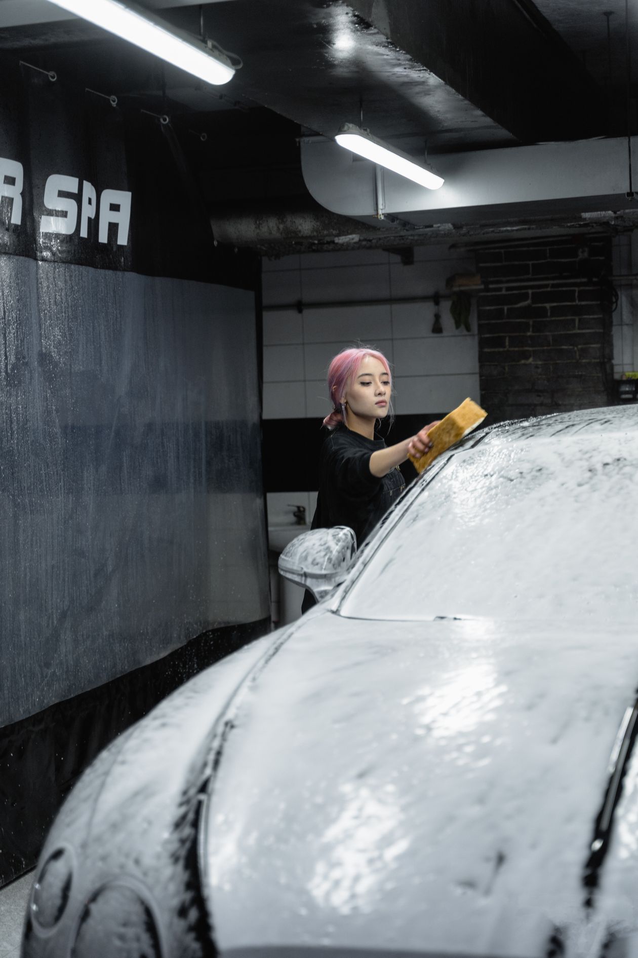 Pessoa lavando o carro com esponja e espuma, contexto de melhor shampoo para lavar carro da Vonixx