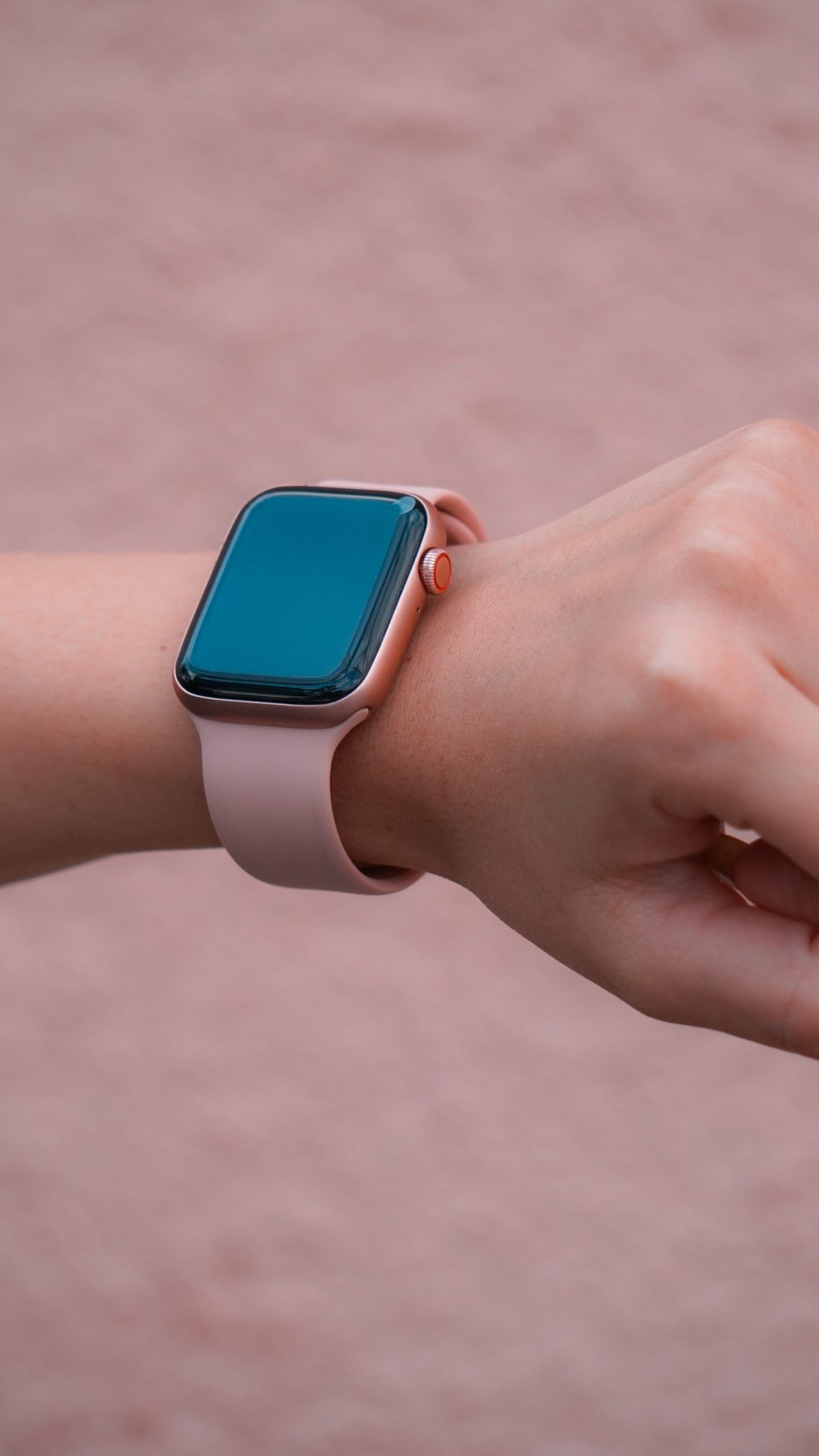 Close-up de smartwatch rosa no pulso feminino com fundo claro, contexto de modelo compacto e discreto