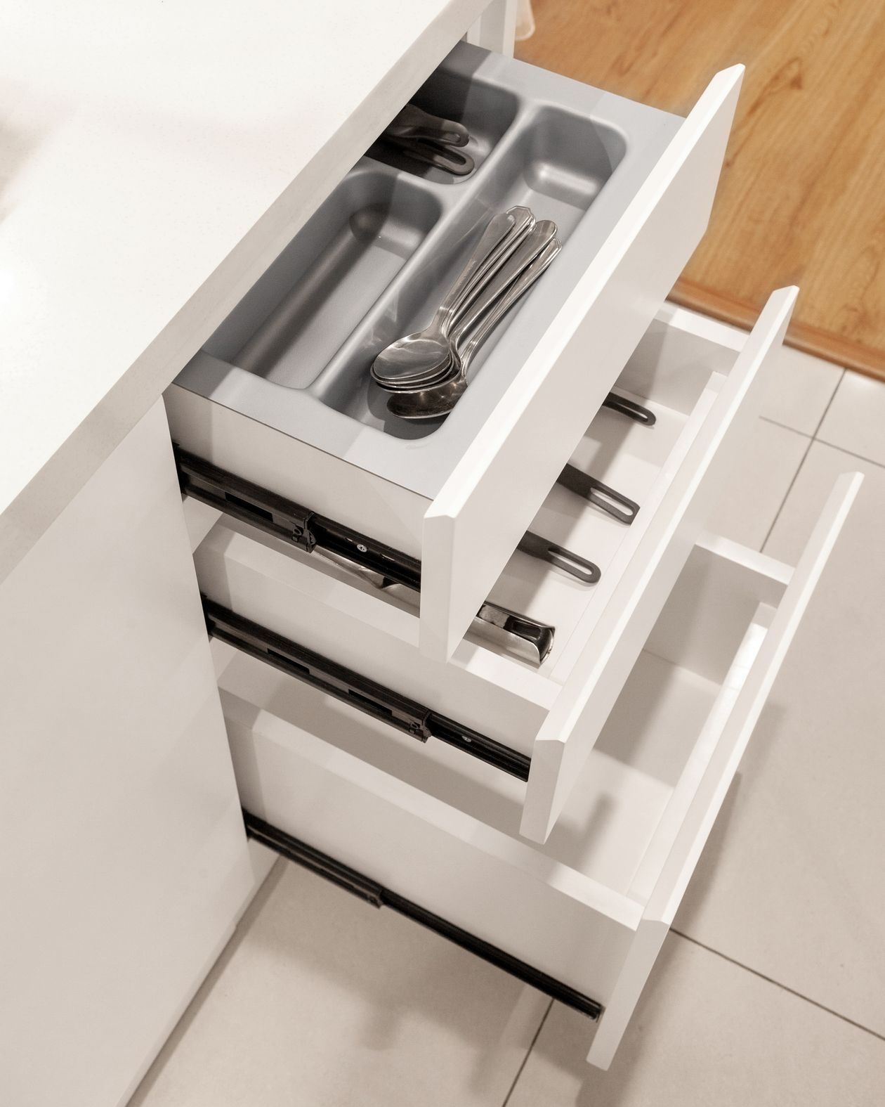 Gaveta de cozinha aberta com utensílios que exigem trava de segurança para bebê