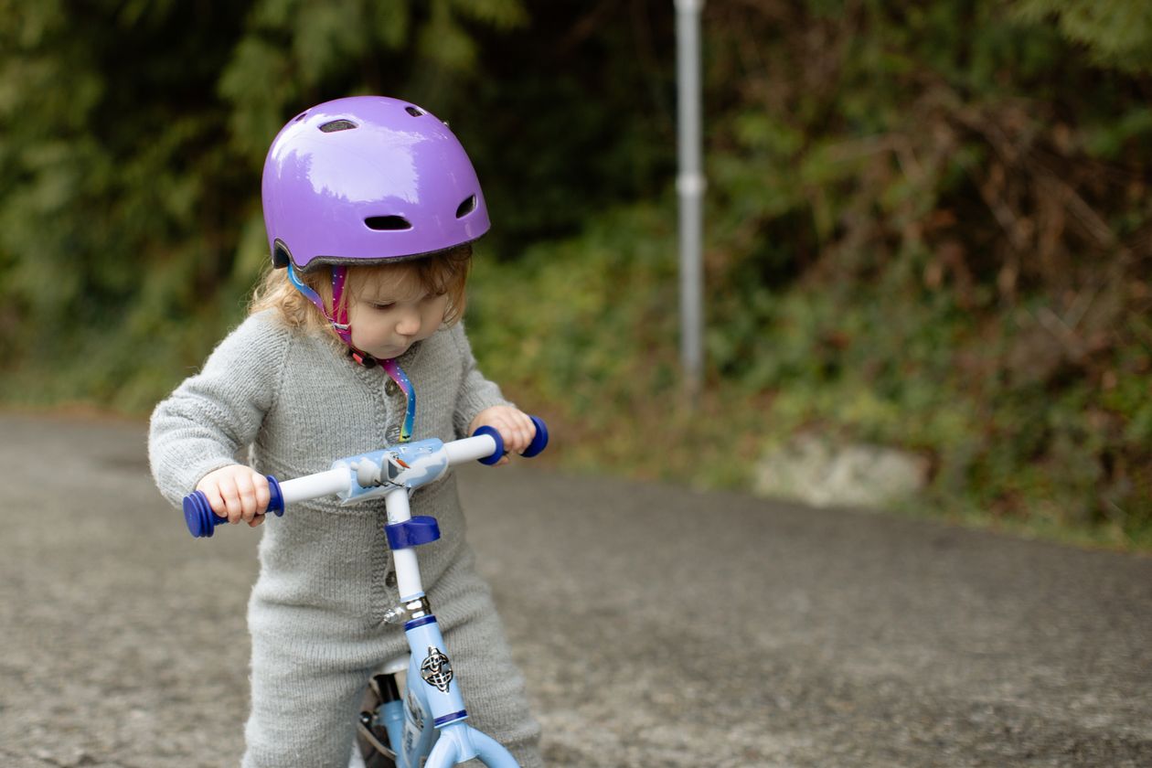 Criança de capacete em veículo de brinquedo no passeio ao ar livre
