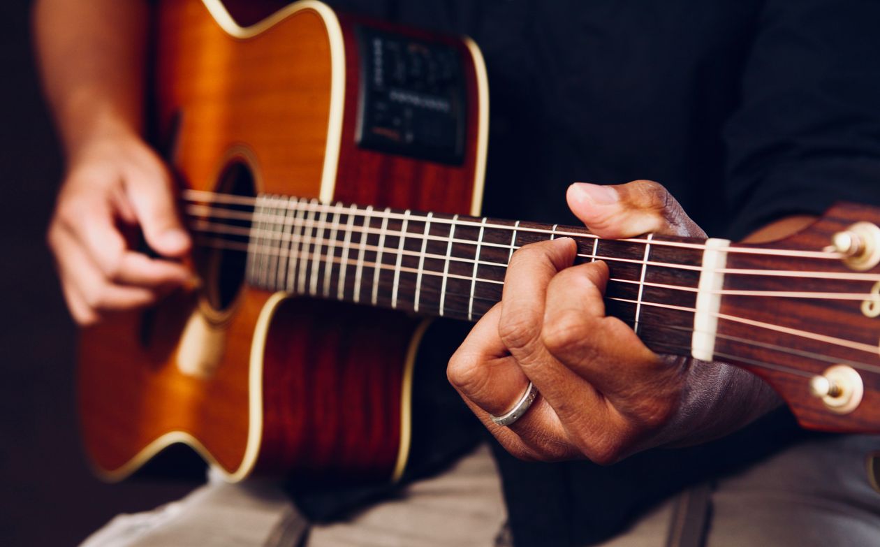 Mãos tocando violão acústico em aula para iniciantes